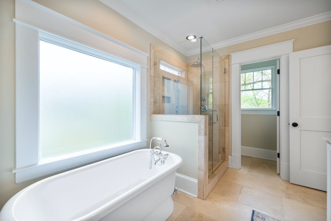 A glass shower enclosure and tub in a bathroom